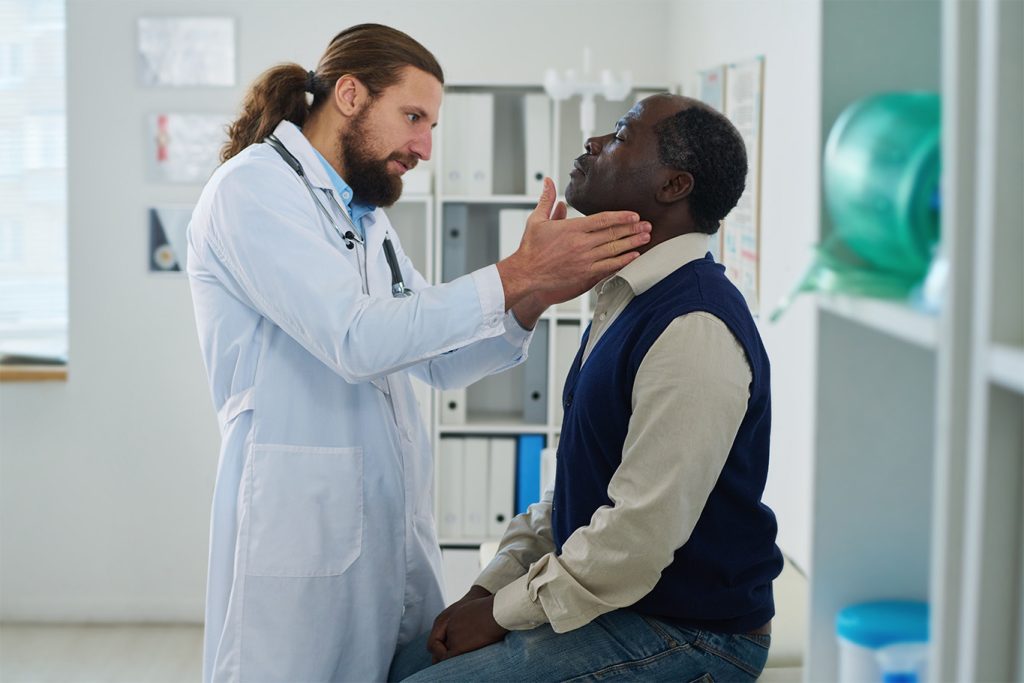 Male doctor examining a senior male patient in a medical office for healthcare assessment.